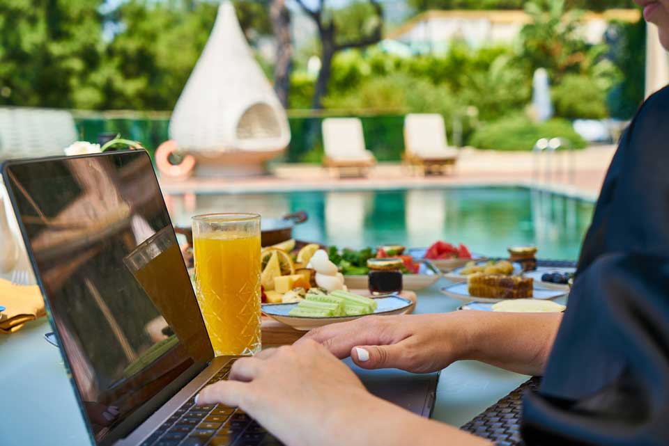 Man working on laptop next to a pool